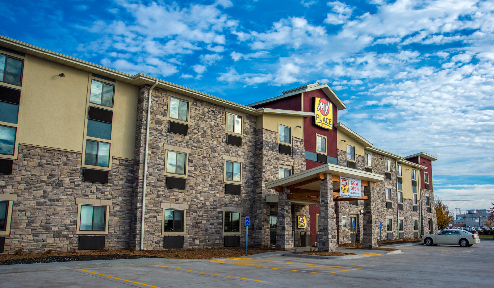 Exterior of My Place Hotel-Altoona, IA under a cloudy, blue sky.