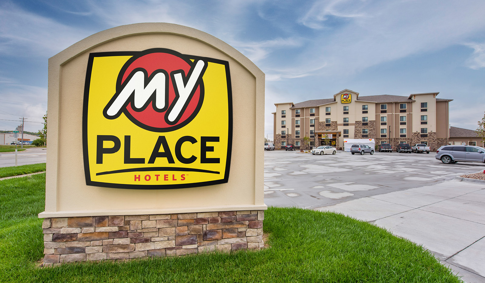 Hotel logo sign with exterior of My Place Hotel-Council Bluffs, IA in the background.