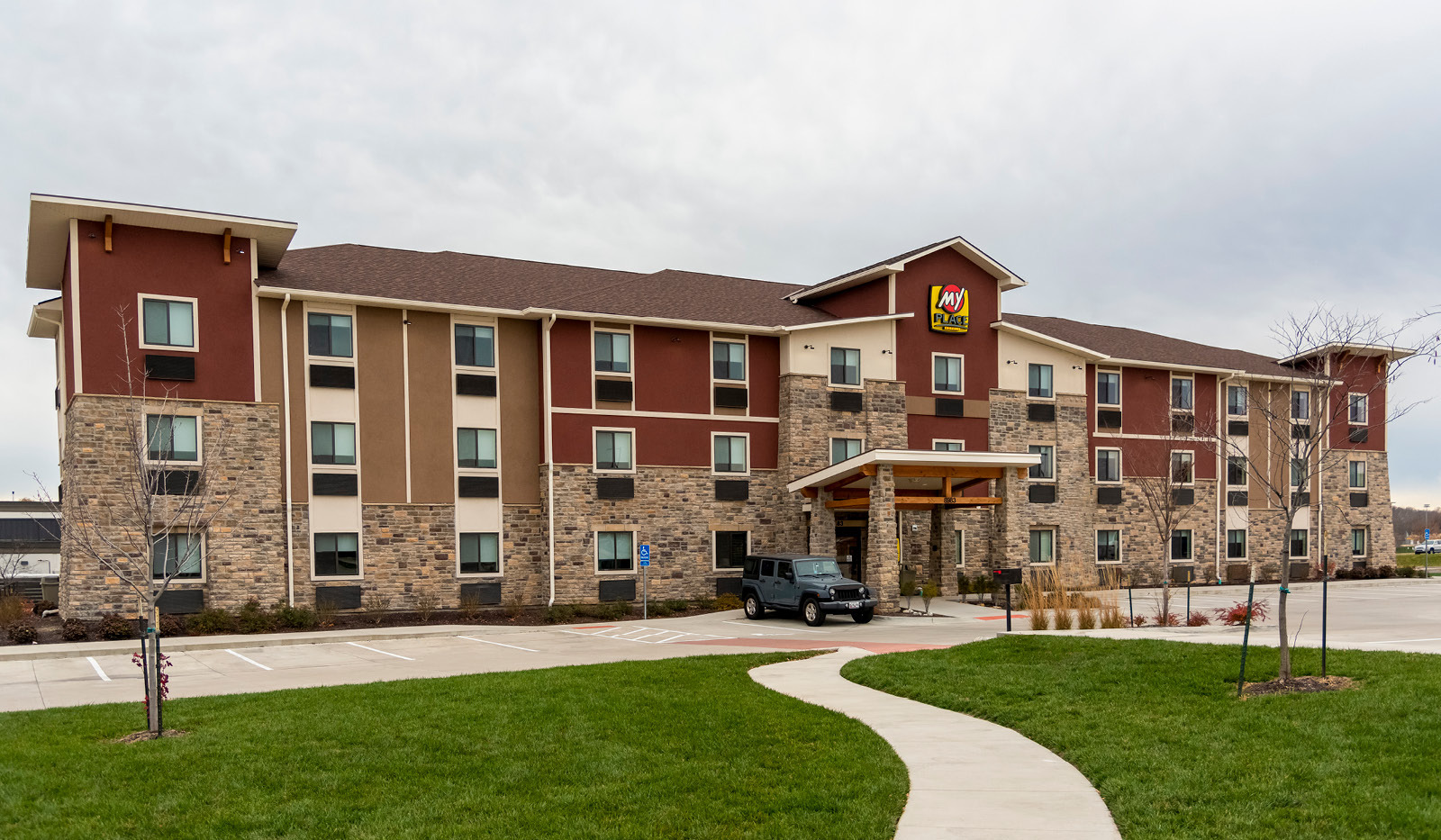 Exterior of My Place Hotel-Overland Park, KS with green grass and sidewalk in the foreground.