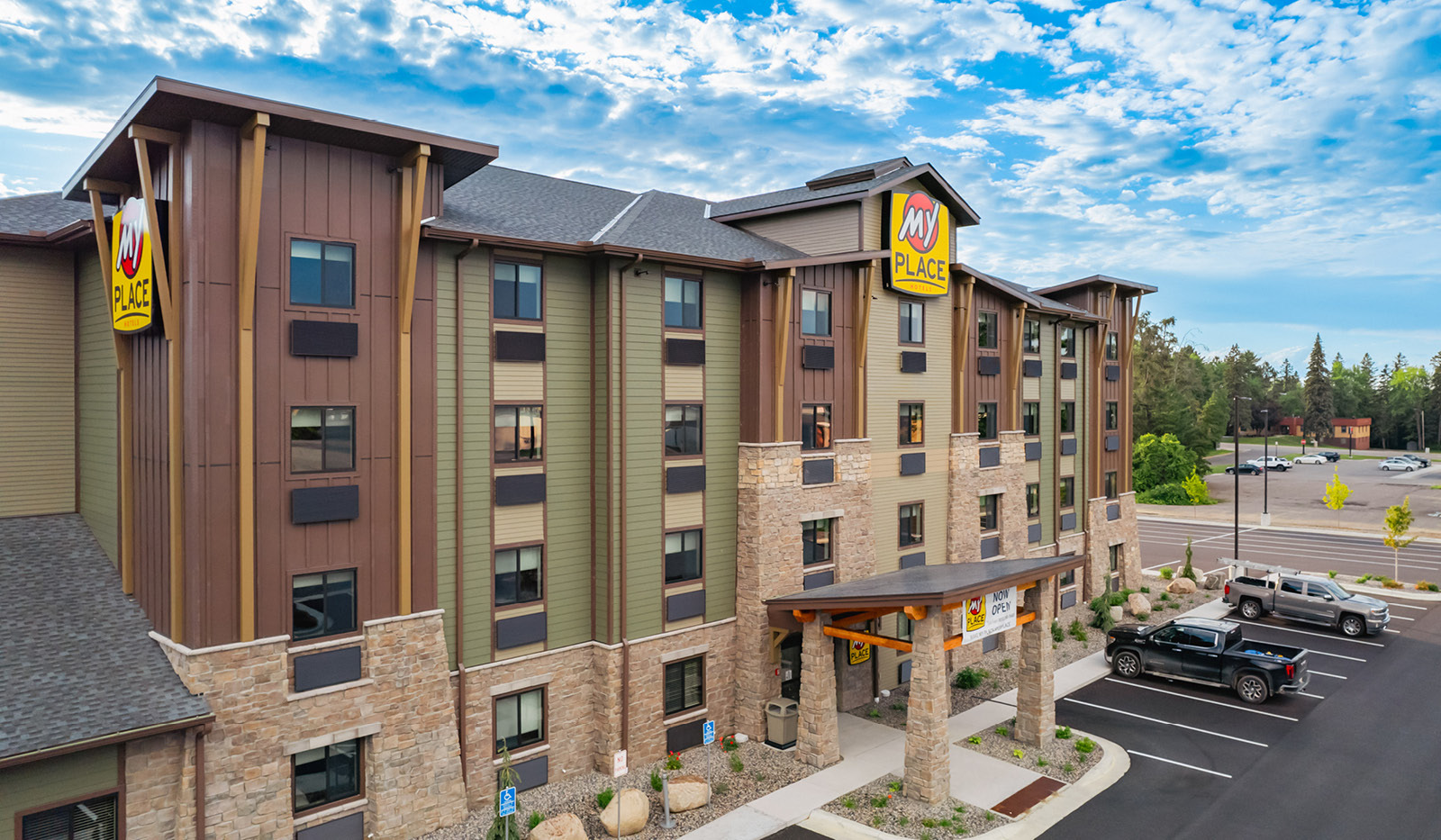 View of the four story brown and green property building with brick detailing and a covered entryway.