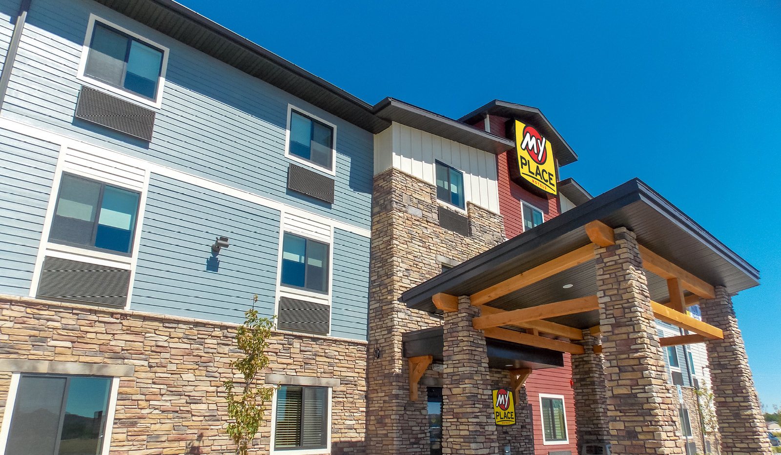 Exterior of My Place Hotel-Billings, MT from ground level looking up at a clear blue sky.