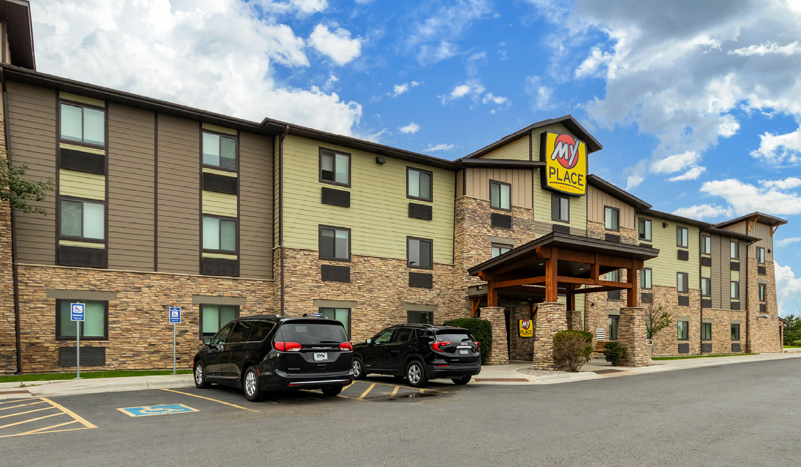 Exterior of My Place Hotel-Bozeman, MT under a cloudy sign.