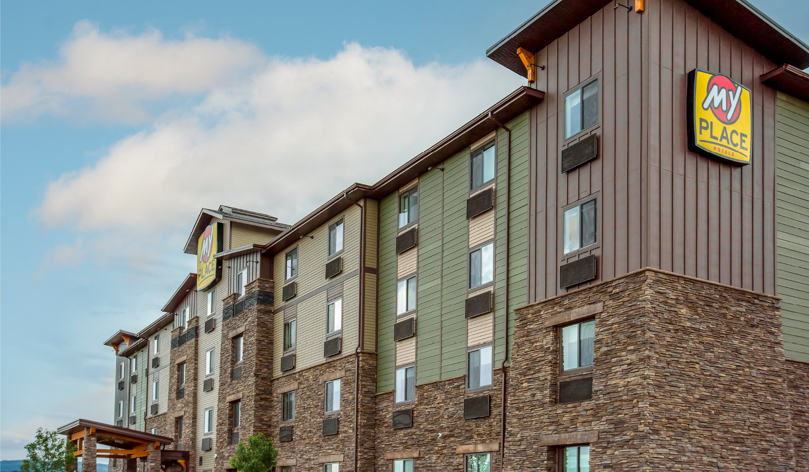 Exterior of My Place Hotel-Kalispell, MT angled up from the corner with two logo signs visible.