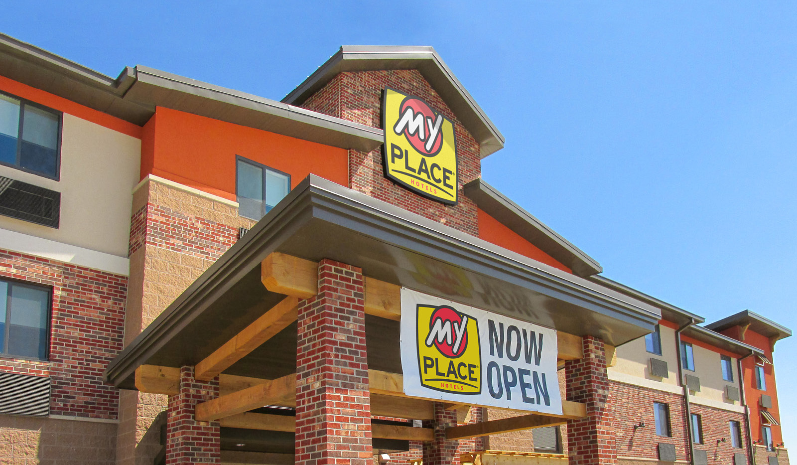 Exterior of My Place Hotel-La Vista, NE with a Now Open banner hanging over the main door.