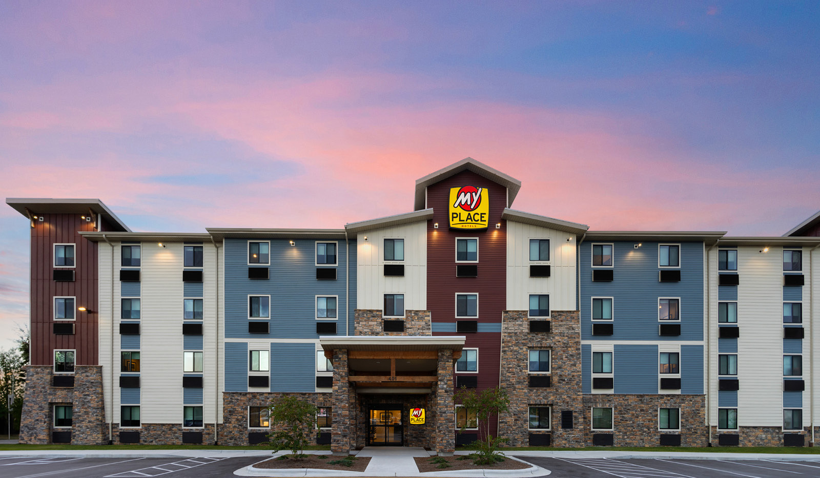 Front view of the hotel with bright pink, purple and blue sunset in the background.