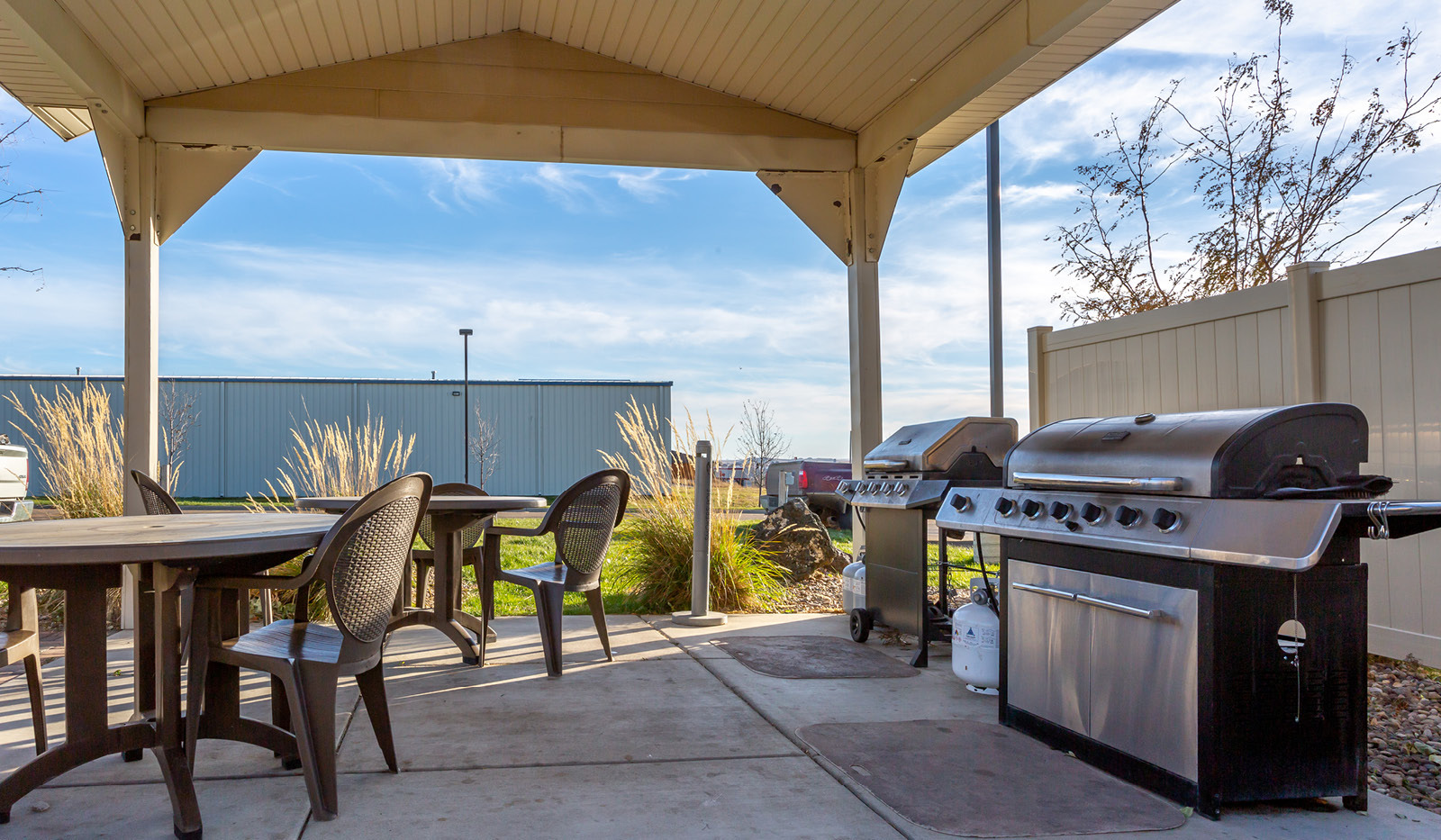 Exterior of My Place Hotel-Dickinson, ND's covered grilling pavilion with grills, tables, and chairs.