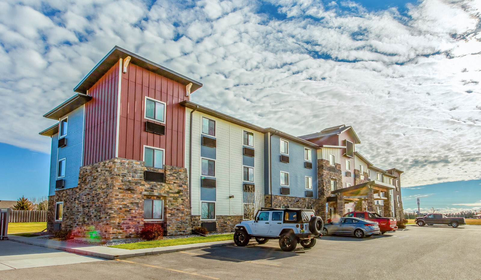Exterior of My Place Hotel-Grand Forks, ND under cloudy blue sky.