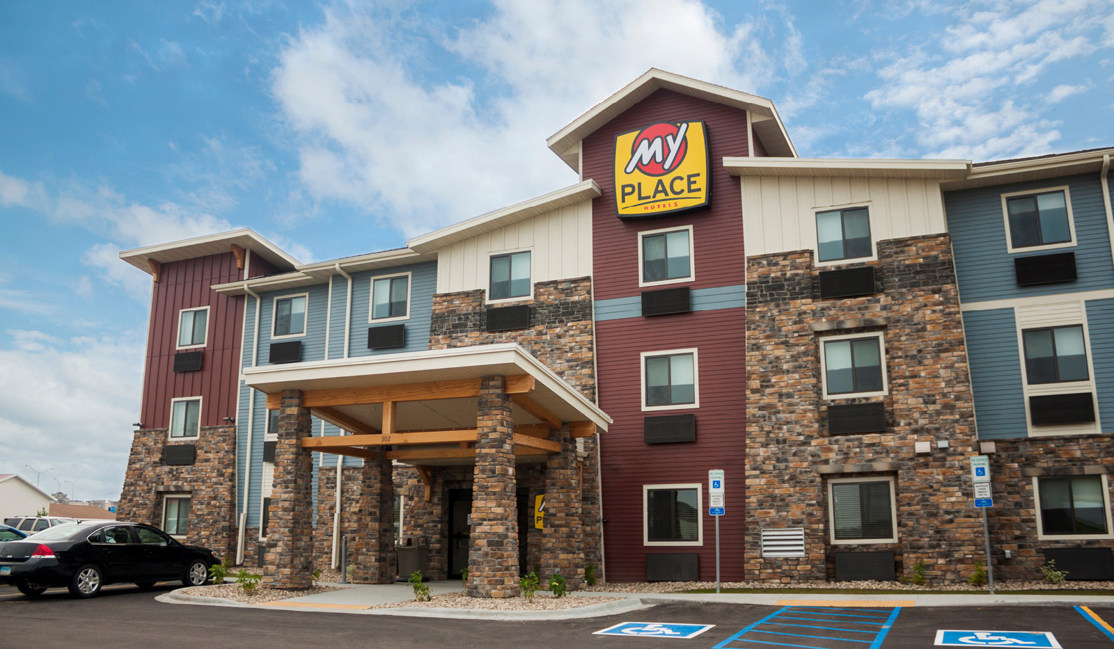 Exterior of My Place Hotel-Jamestown, ND under a partly cloudy blue sky.