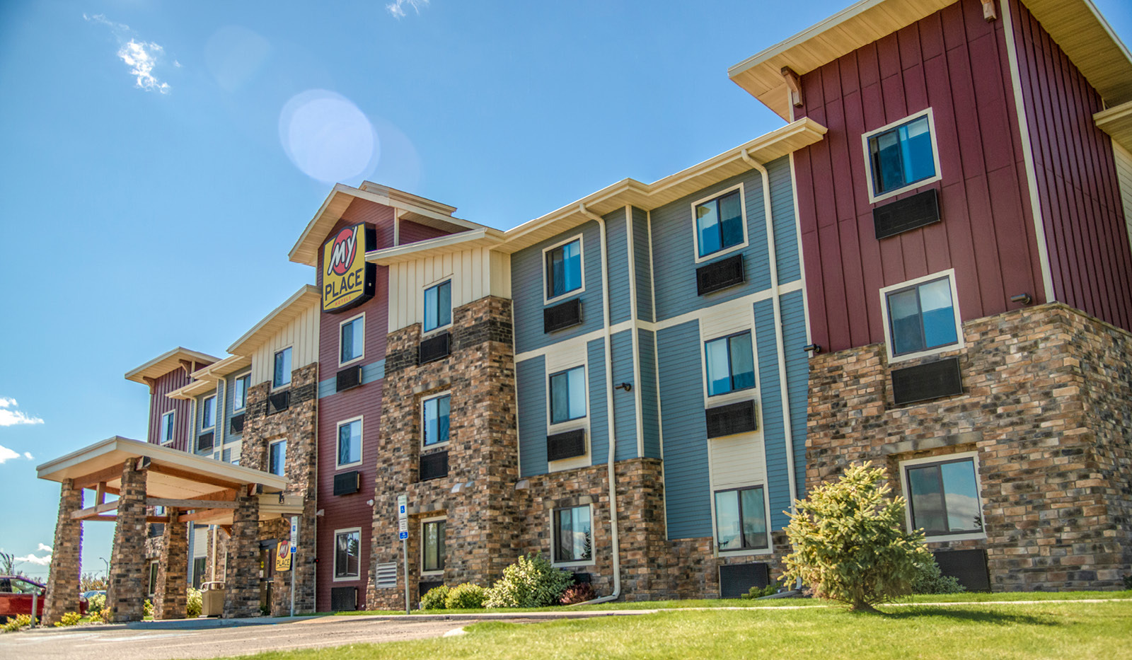 Exterior of My Place Hotel-Jamestown, ND from ground view up showing a clear blue sky.