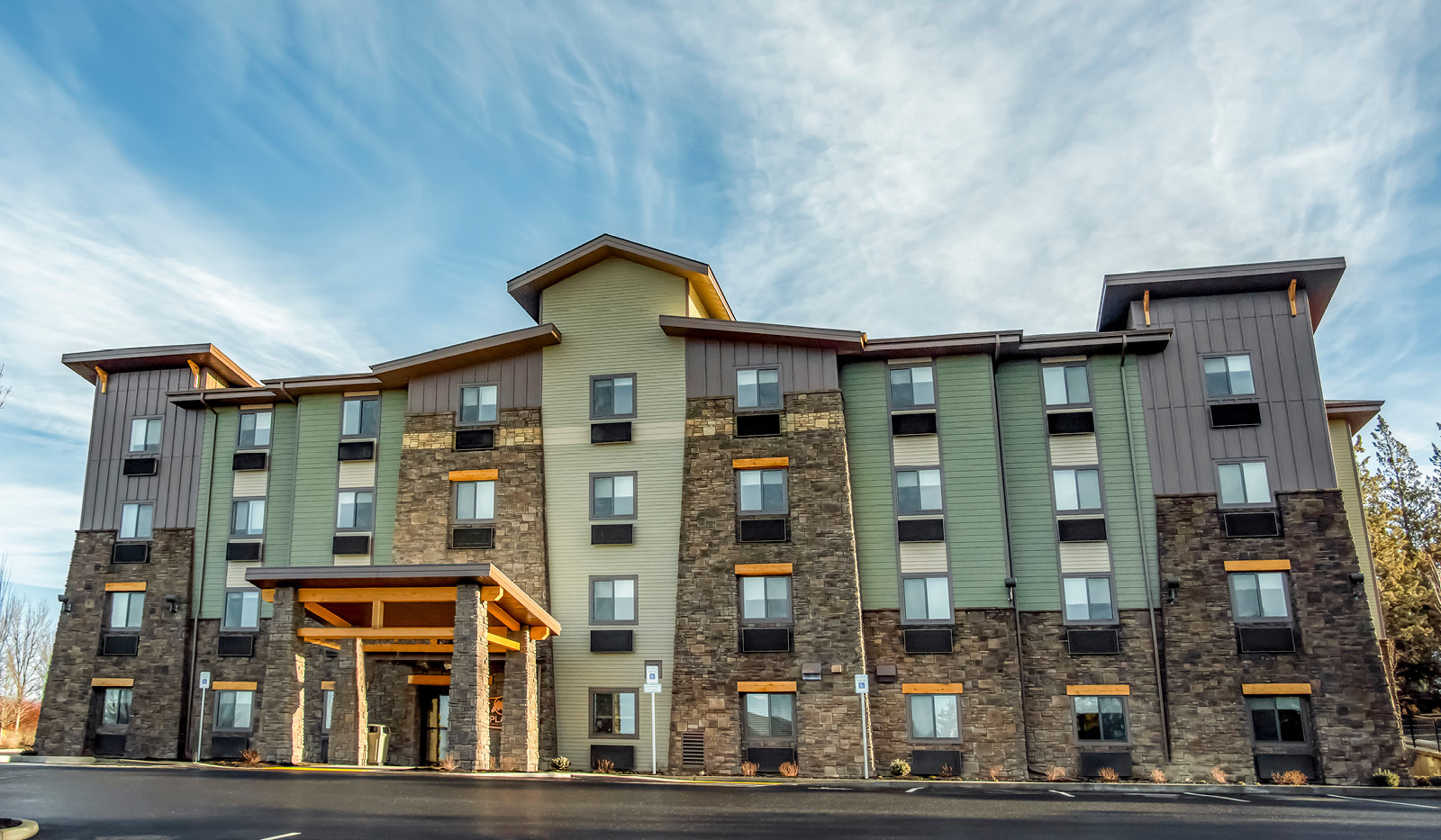 Exterior of My Place Hotel-Bend, OR under a partly cloudy blue sky.