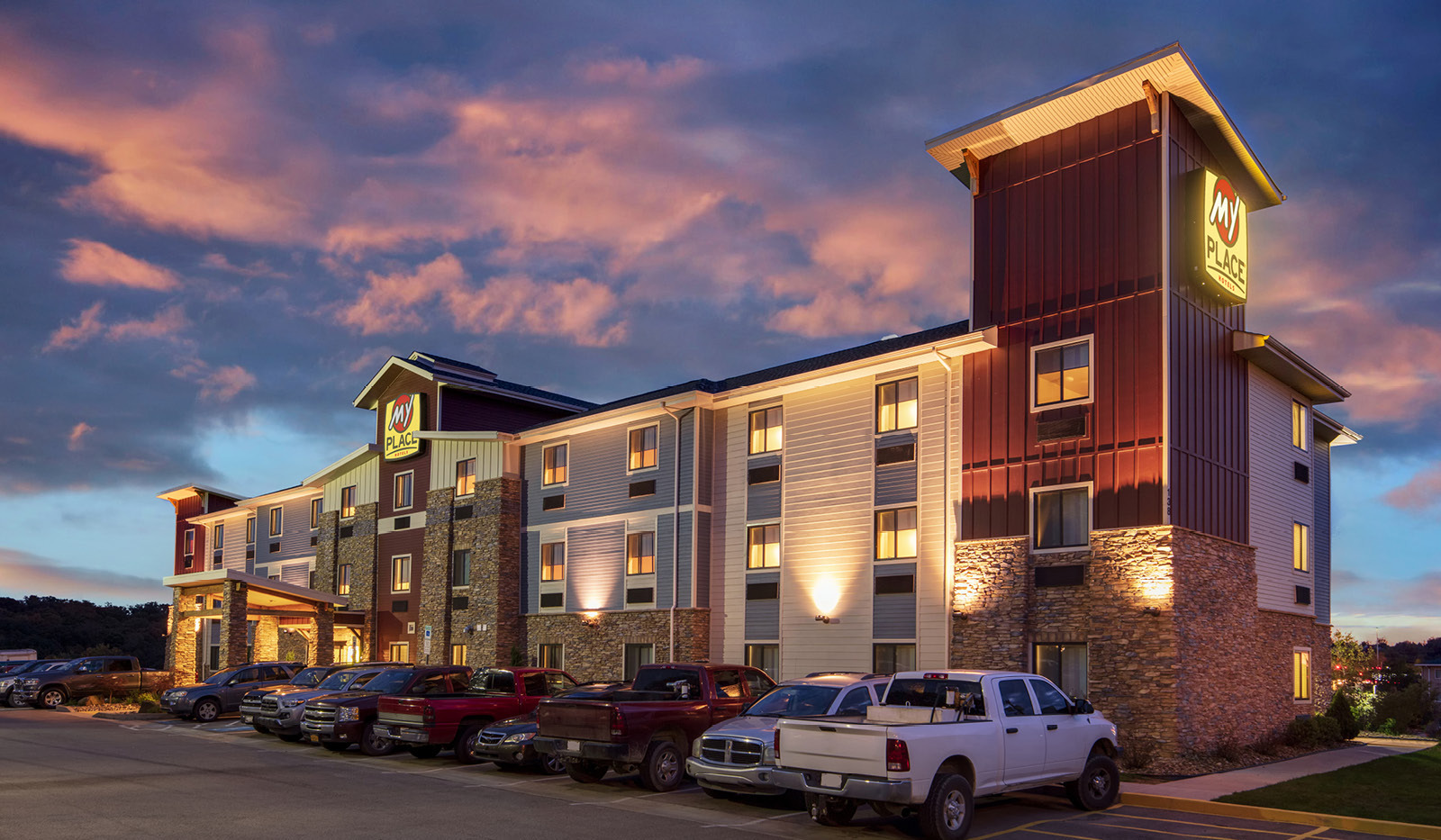 Exterior of My Place Hotel-Monaca, PA illuminated at dusk under a pink and purple sunset.