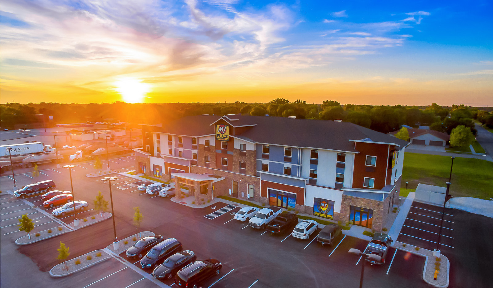 Birds eye view of hotel and parking lot with sunset background.