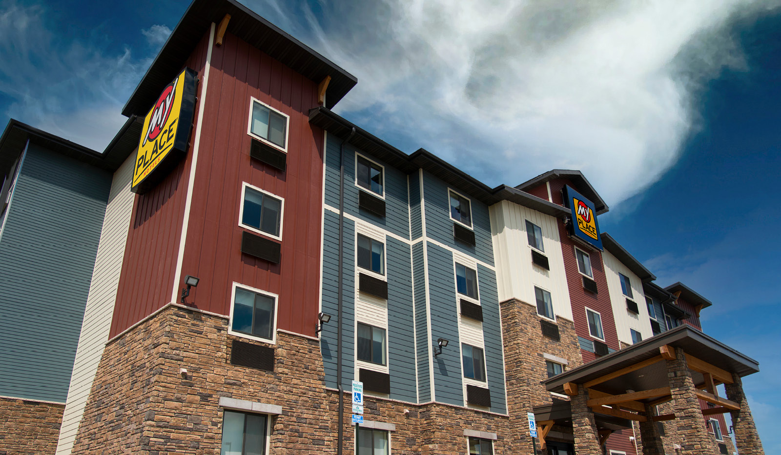 Exterior of My Place Hotel-Brookings, SD from ground looking up at partly cloudy sky.