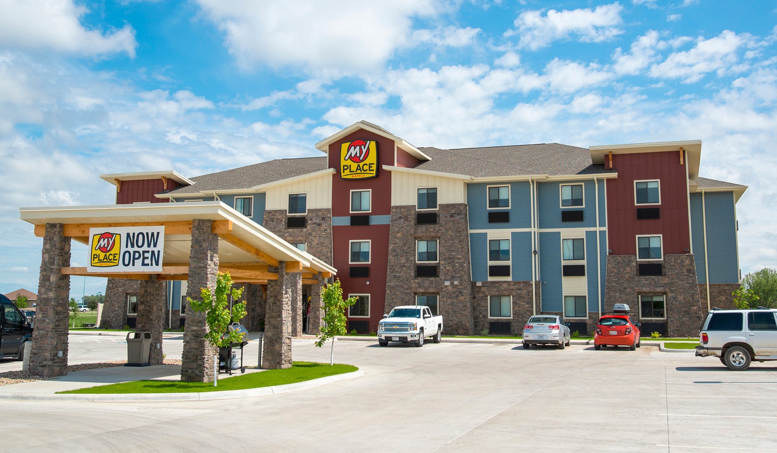 Wide exterior of My Place Hotel-Ft. Pierre, SD showing parking lot and grilling pavilion.
