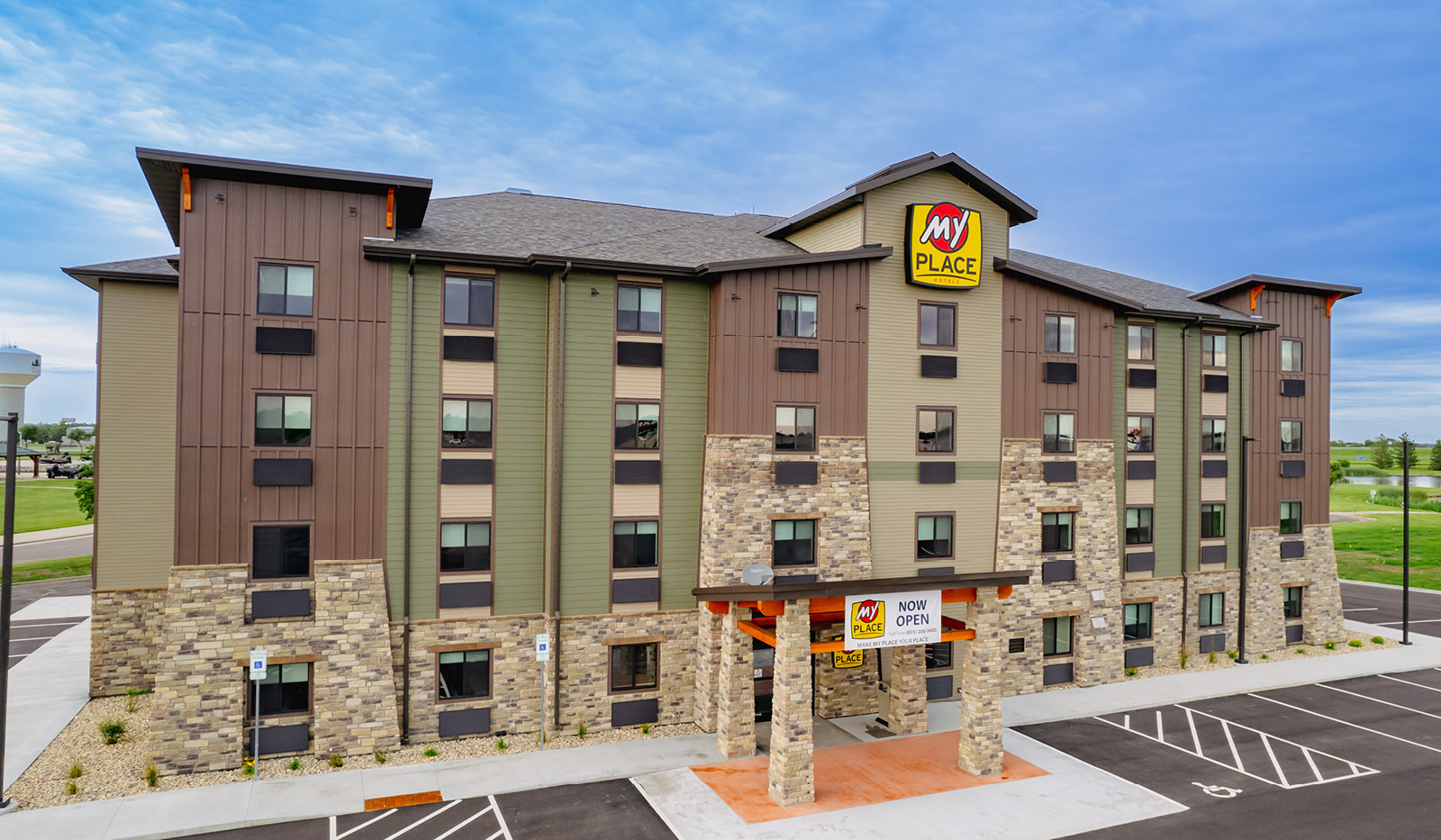 Front view of 4 story green and brown building with brick detailing.