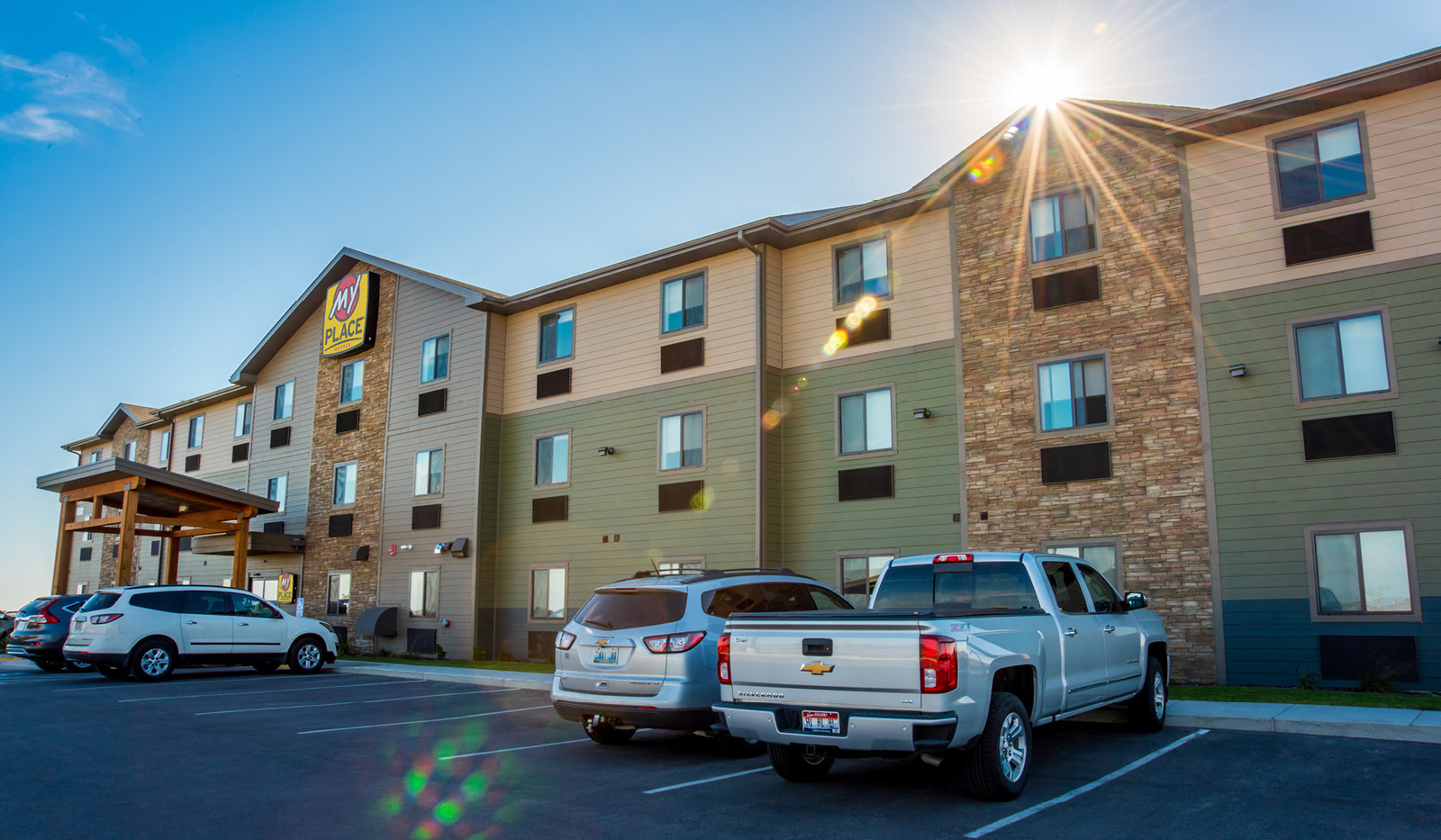 Exterior of My Place Hotel-Rapid City, SD with sun peeking from behind hotel.
