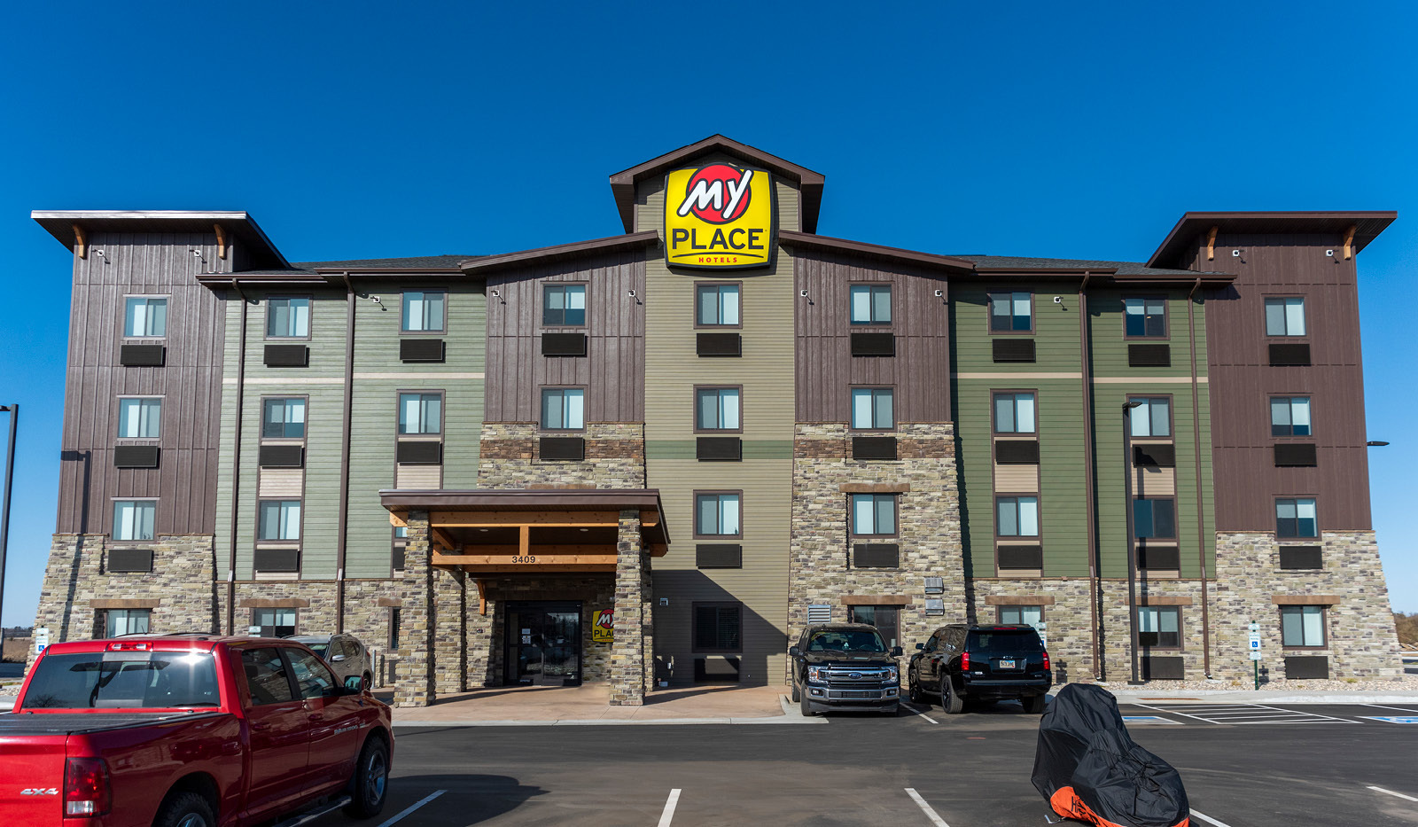 Wide exterior of My Place Hotel-Watertown under a clear blue sky.