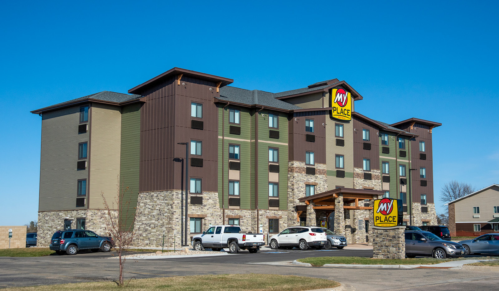 Wide exterior of My Place Hotel-Watertown under a clear blue sky.