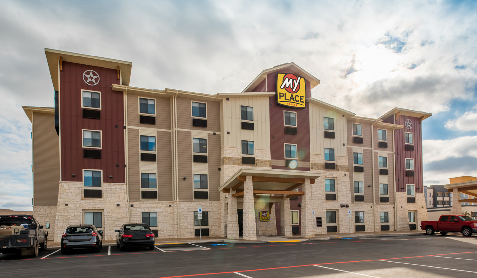 Wide exterior of My Place Hotel-Lubbock, TX under a cloudy sky.