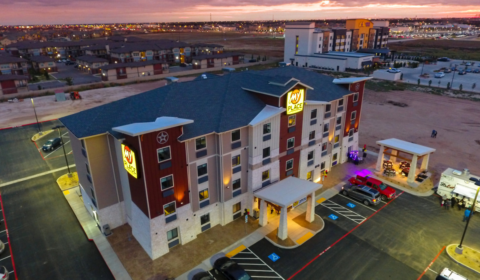 Drone exterior of My Place Hotel-Lubbock, TX illuminated at dusk.