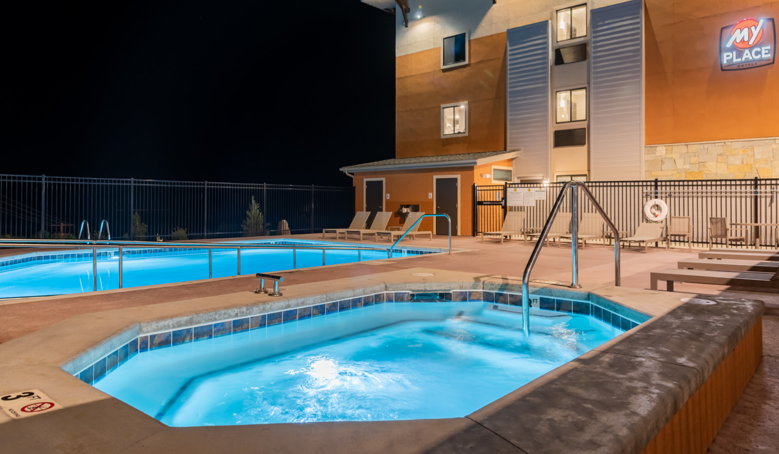 Exterior My Place Hotel-Moab, UT pool and hot tub illuminated at night.