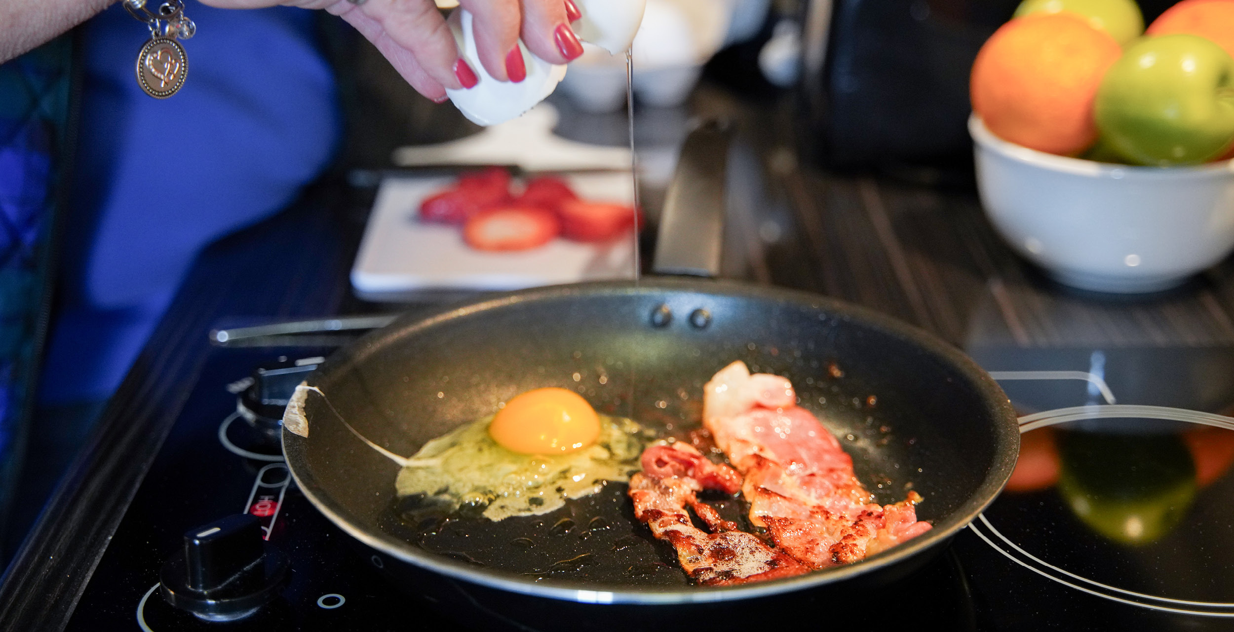 Bacon and an egg frying in a pan on the two burner cooktop.
