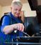 Women wearing a stylish blue shirt and vest cooking on the two burner stove top in the in-room kitchen.