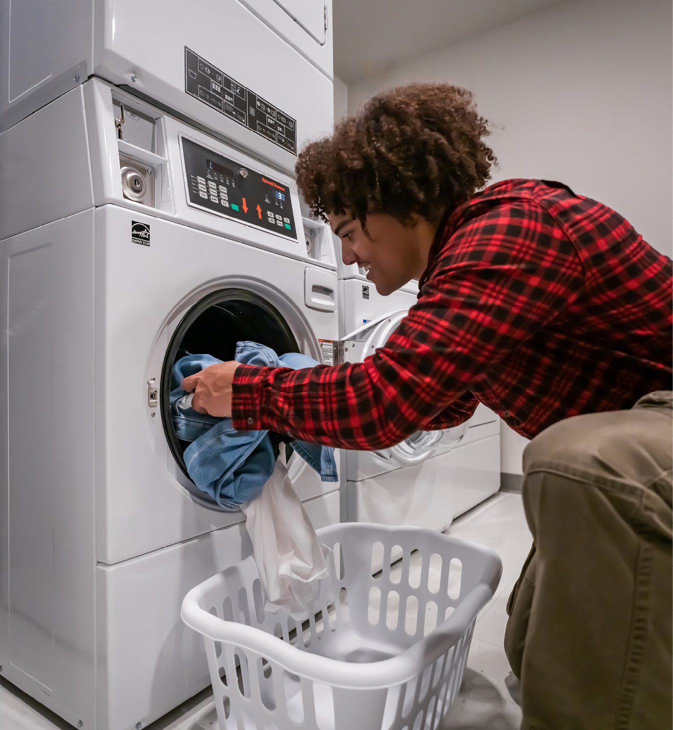 Man taking clean clothes out of the dryer in the 24/7 on-site laundry facility.