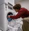 Man taking clean clothes out of the dryer in the 24/7 on-site laundry facility.