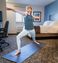 Women in My Place Hotel room on a black yoga mat standing in a warrior yoga pose.