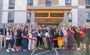 Professionals are standing in front of the new hotel with arms in the air for the ribbon cutting.