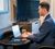 Man sitting at the moveable desk in the hotel room working on his laptop.