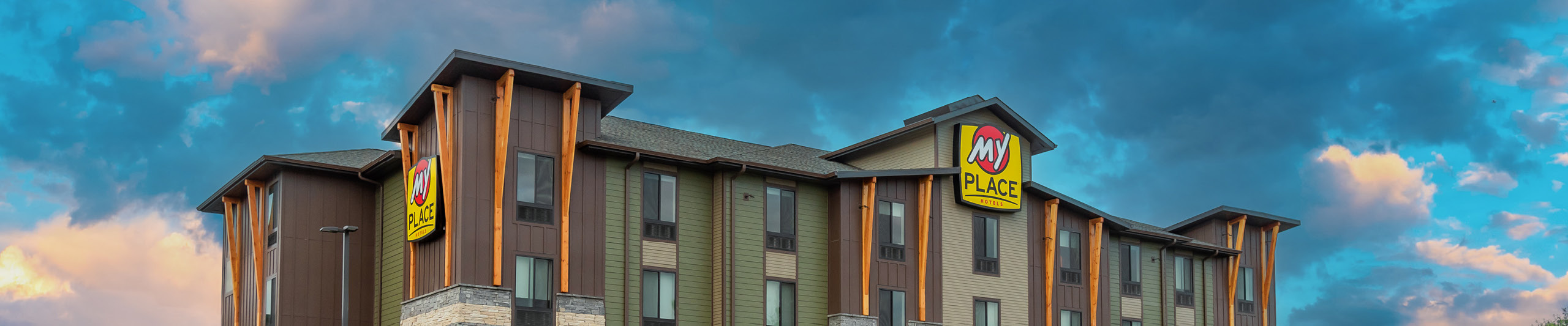 Top half of My Place Hotel exterior with blue cloudy sky.