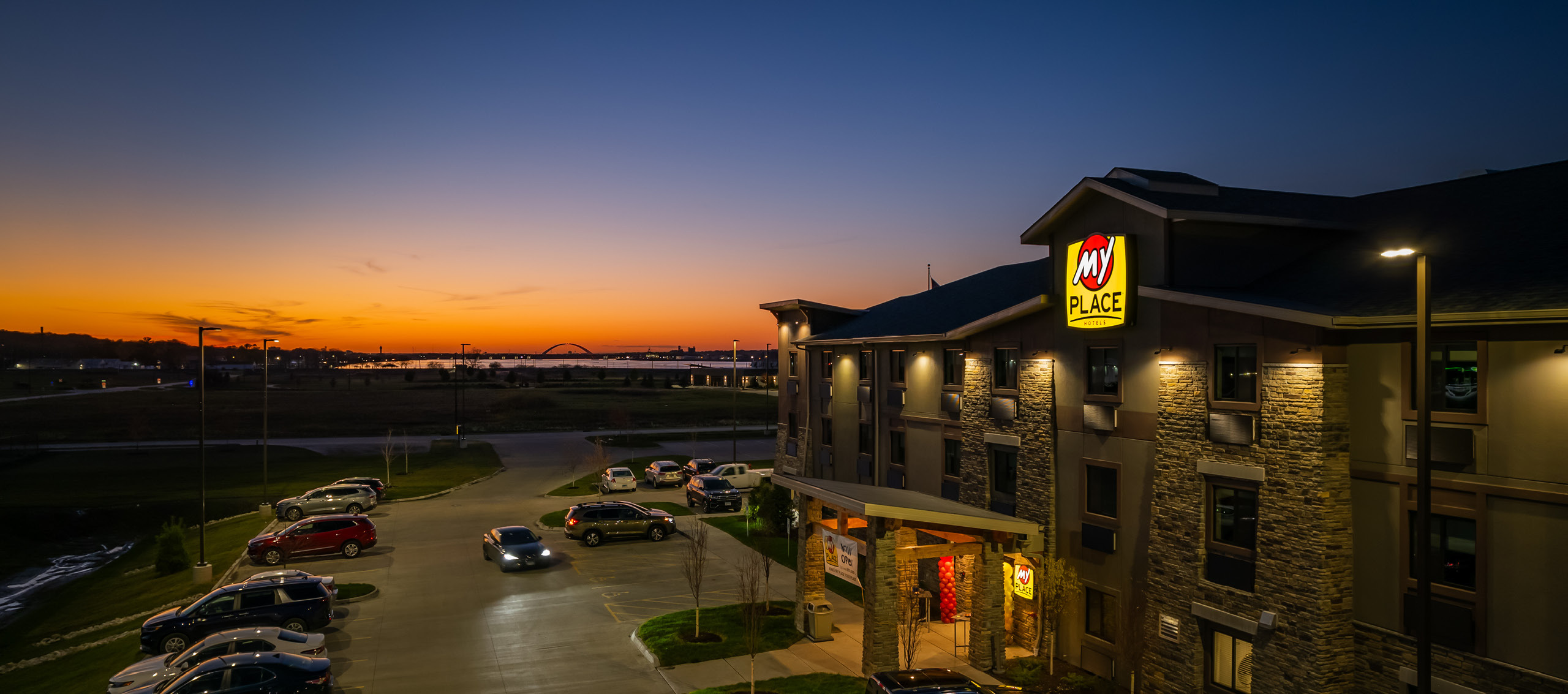 Drone shot of My Place Hotel at night with blue and orange sunset in the background.
