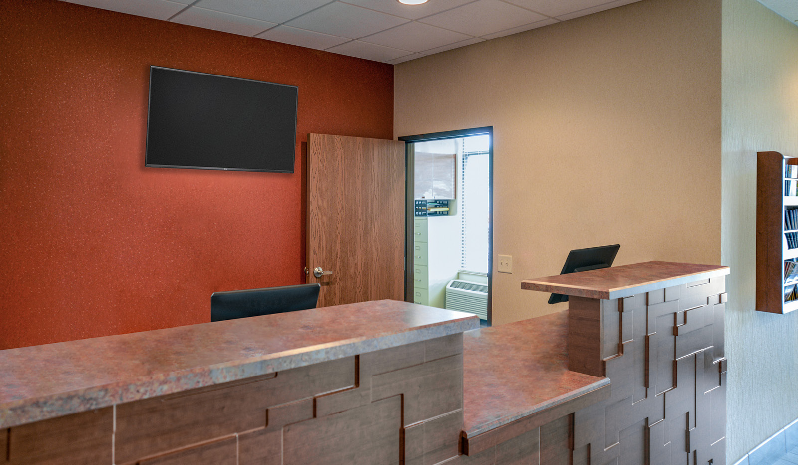 My Place Hotel lobby front desk with television and door to manager's office.