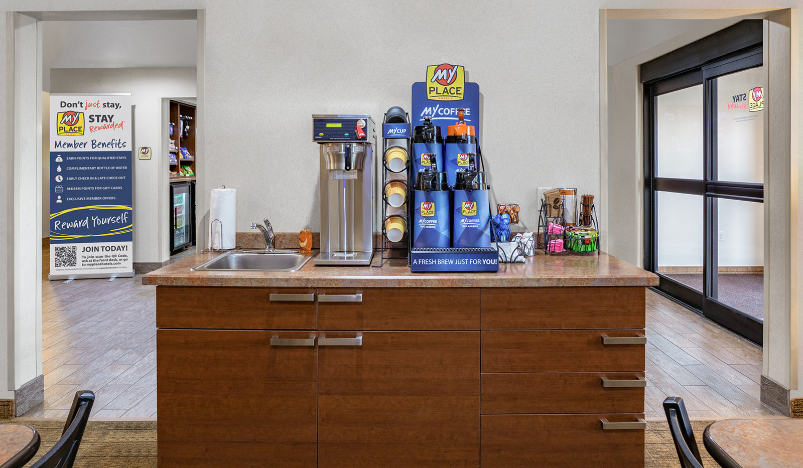 Coffee station including three coffee carafes, one decaf carafe, cream, sugar, cups, and sink.