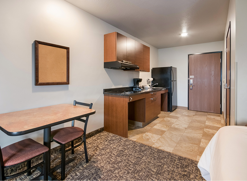 Interior of My Place hotel room with table, chairs, and wheelchair-accessible kitchenette.