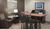 Interior lobby with bar-height table and chairs, two brown recliners, small table and lamp, and shared computer station.