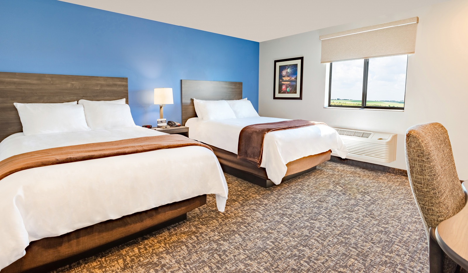 Interior room with two queen beds, rolling desk and office chair before a blue accent wall.