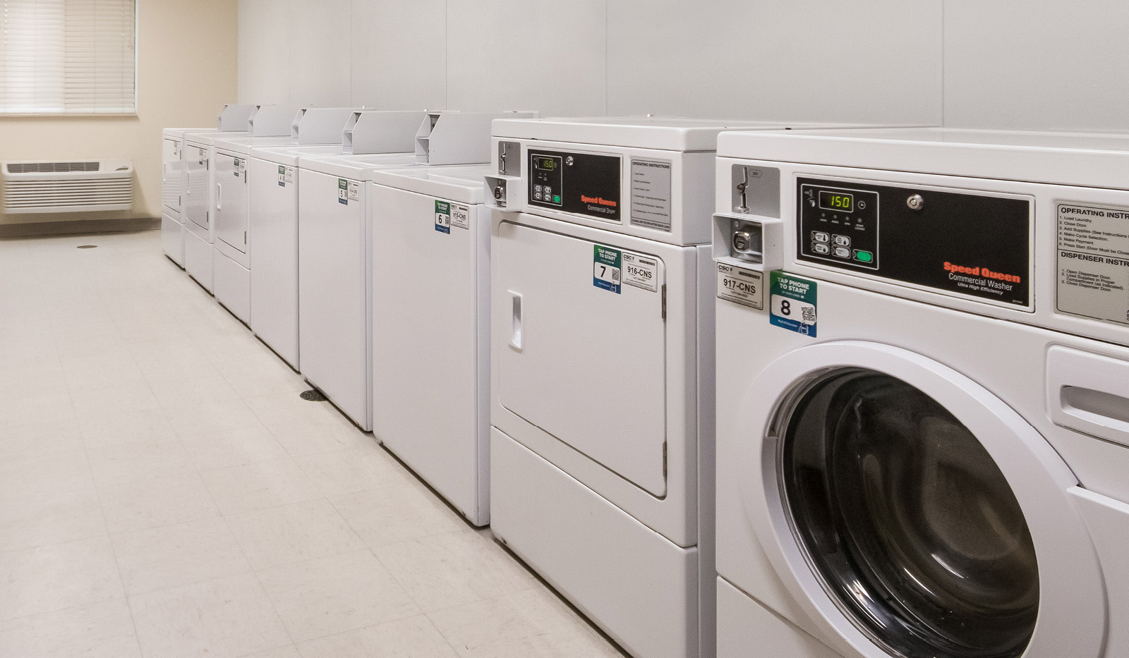 Interior laundry facility with eight coin-operated washers and dryers.