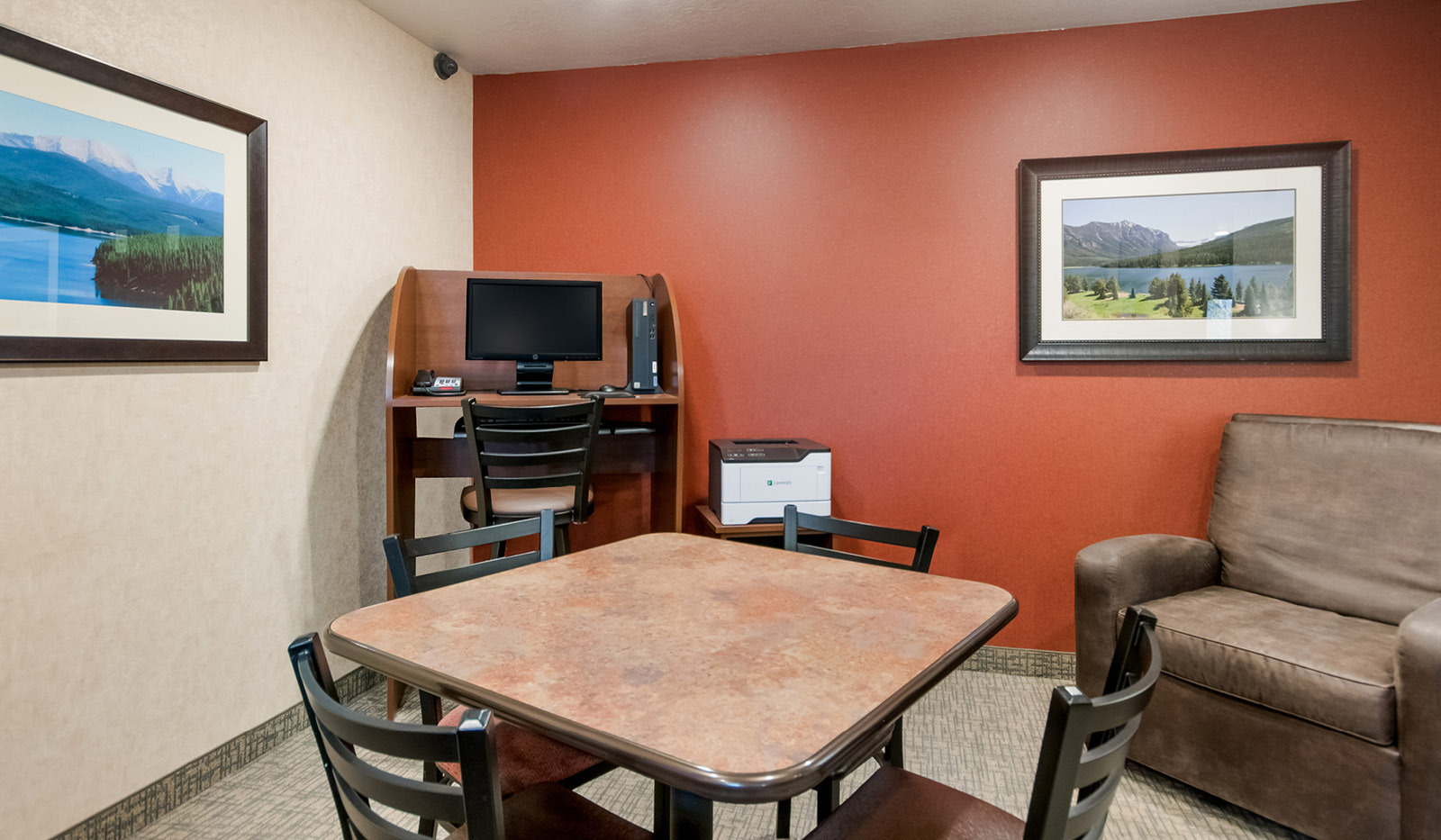 Interior lobby lounge area with table and chairs, shared computer desk, and brown recliner.