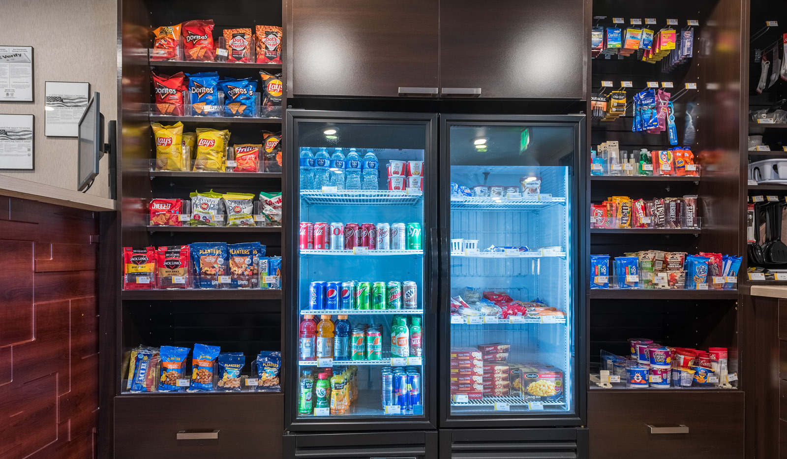 Interior lobby My Store with three racks of snacks and toiletries flanking two coolers filled with drinks and cold foods.