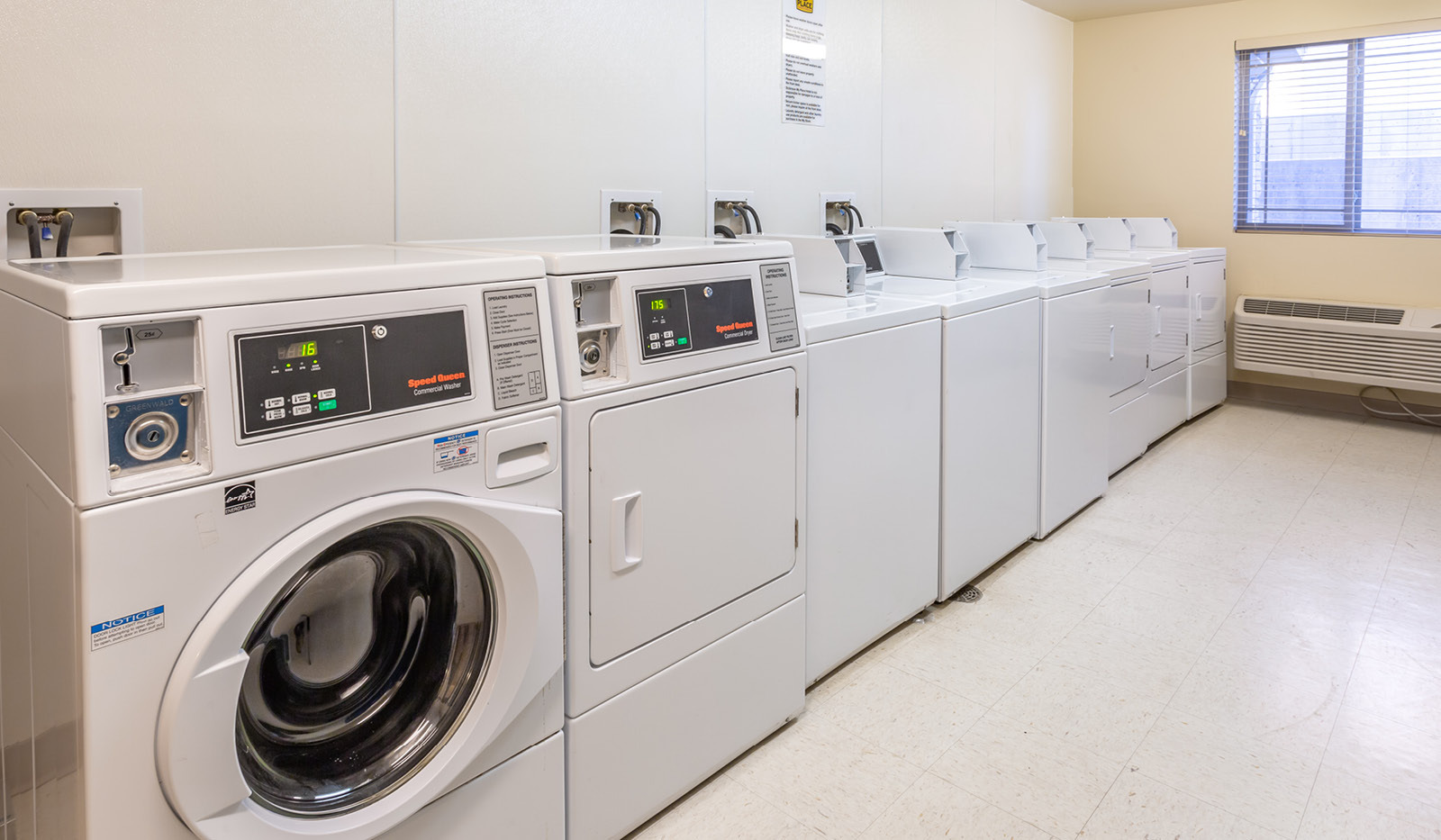 Interior laundry facility with row of coin-operated washers and dryers.