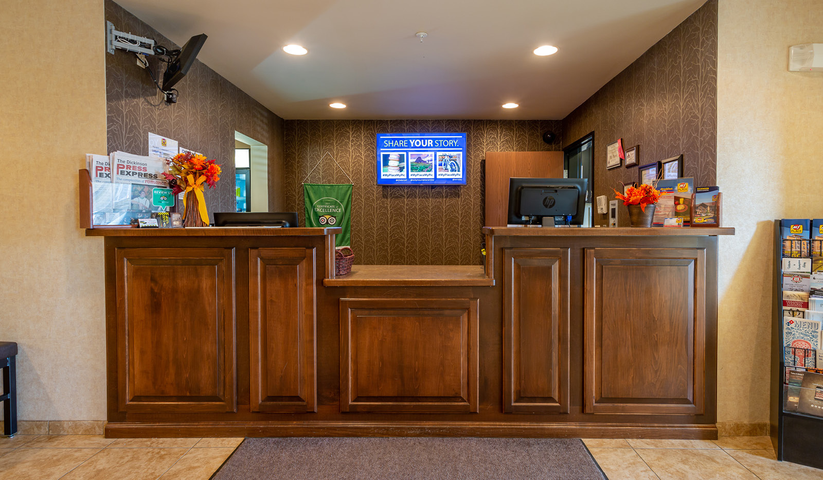 Interior lobby area's brown front desk with mounted TV behind desk.