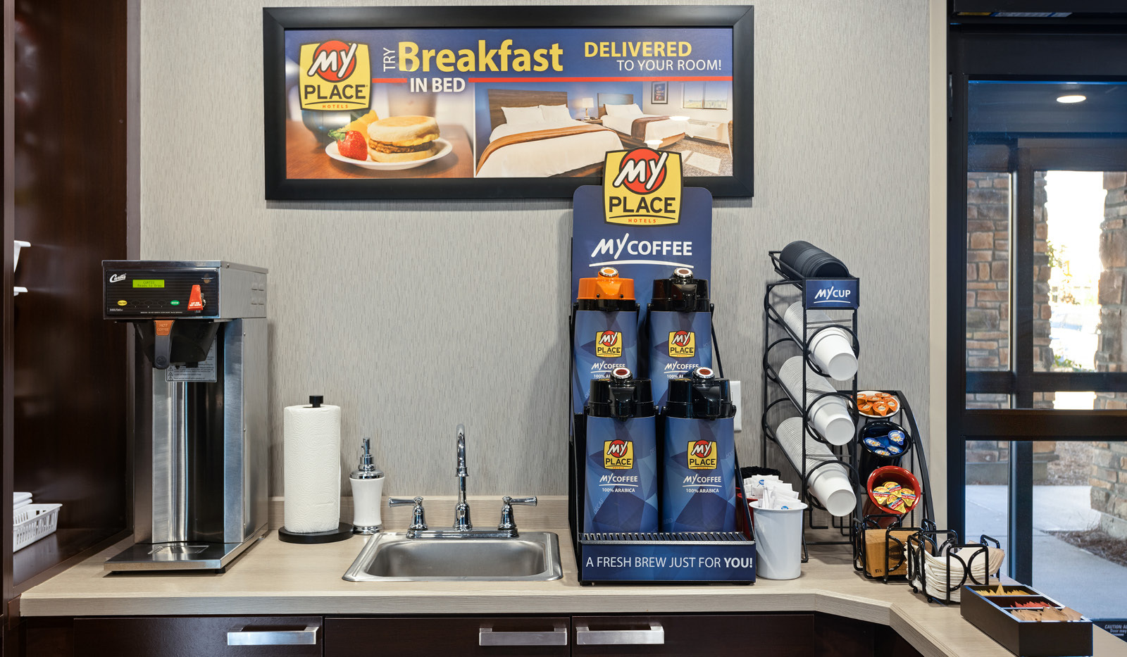 Coffee station with three regular and one decaf coffee carafe filled with hot coffee. Coffee creamer, cups, lids and straws are available.
