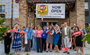 A group of people ribbon cutting while confetti is in the air.
