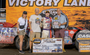 Four people posing for a photo at a racing competition.