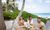 Three people sitting at an outdoor table eating, with an ocean background.