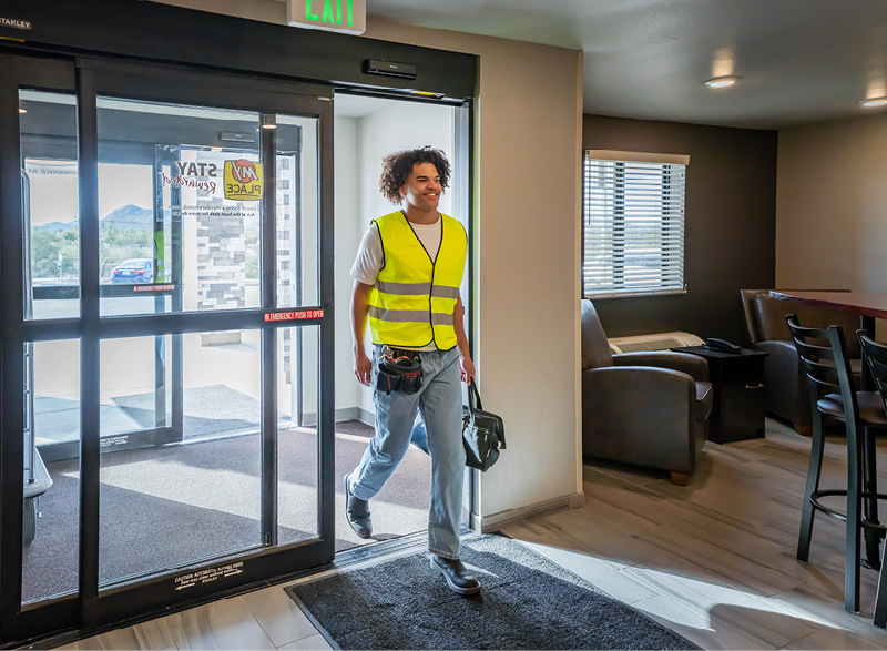 Man in florescent vest entering lobby of My Place Hotel.