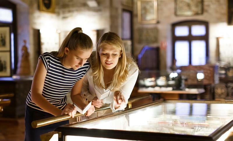 Two women looking down at a glass exhibit case.